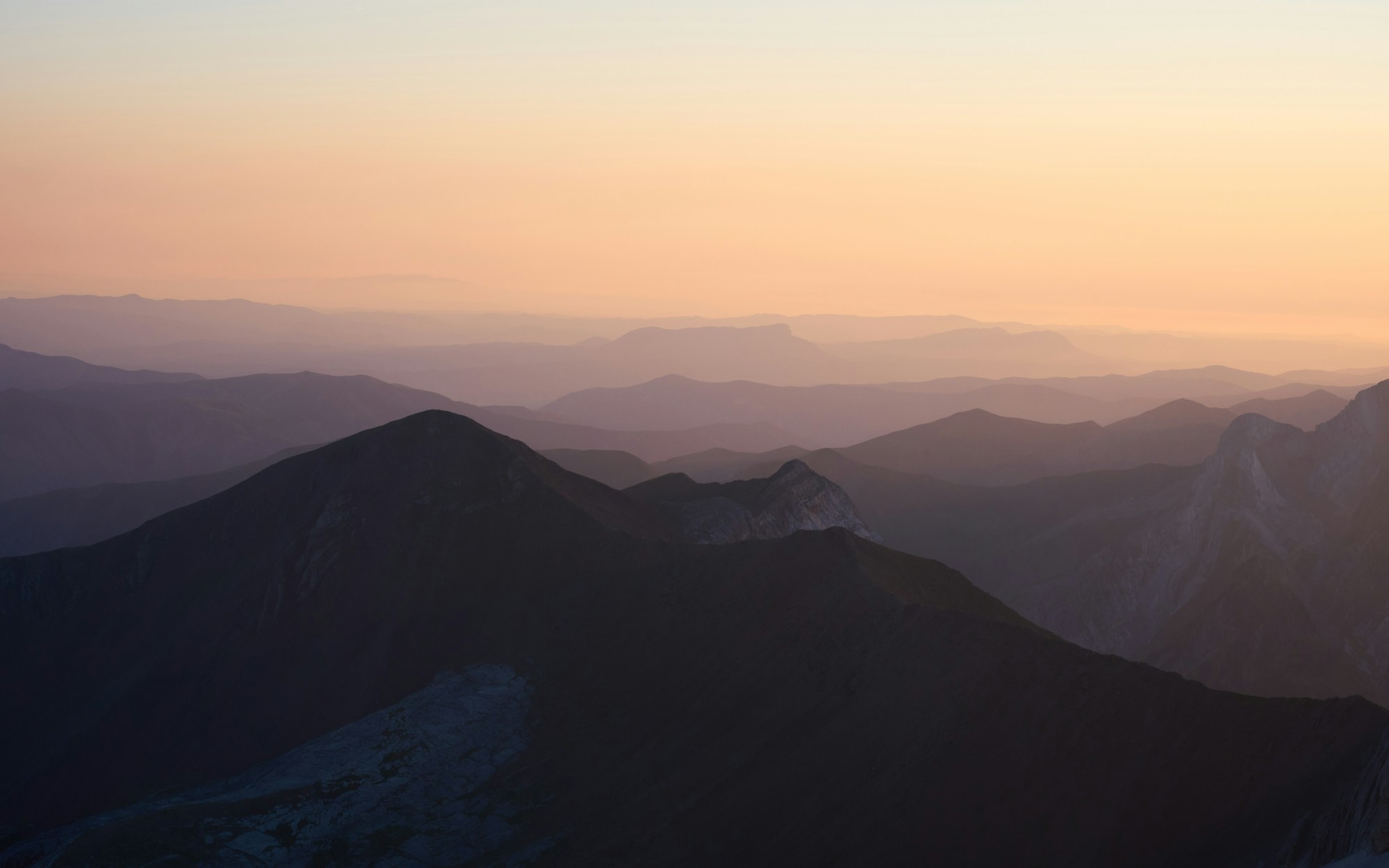 Layered mountain ridges beneath a luminous morning sky
